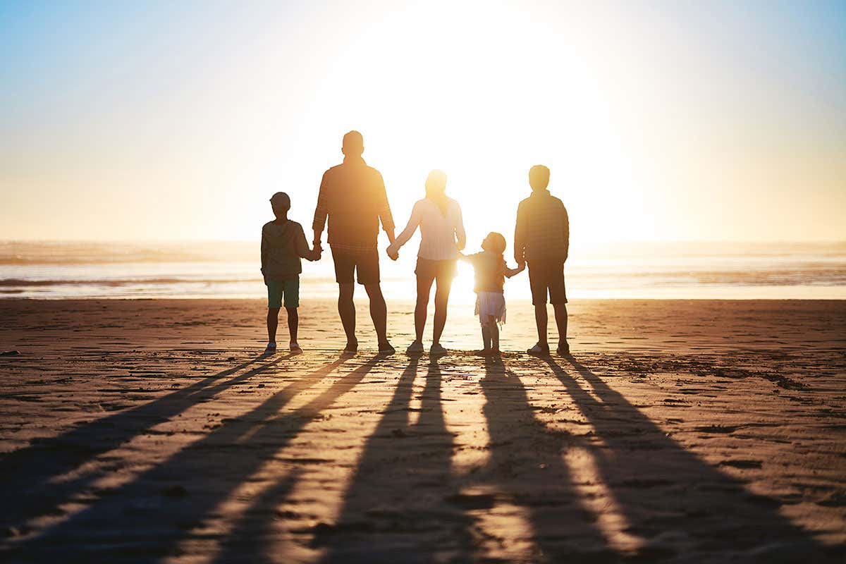 Family silhouetted on sunlit beach
