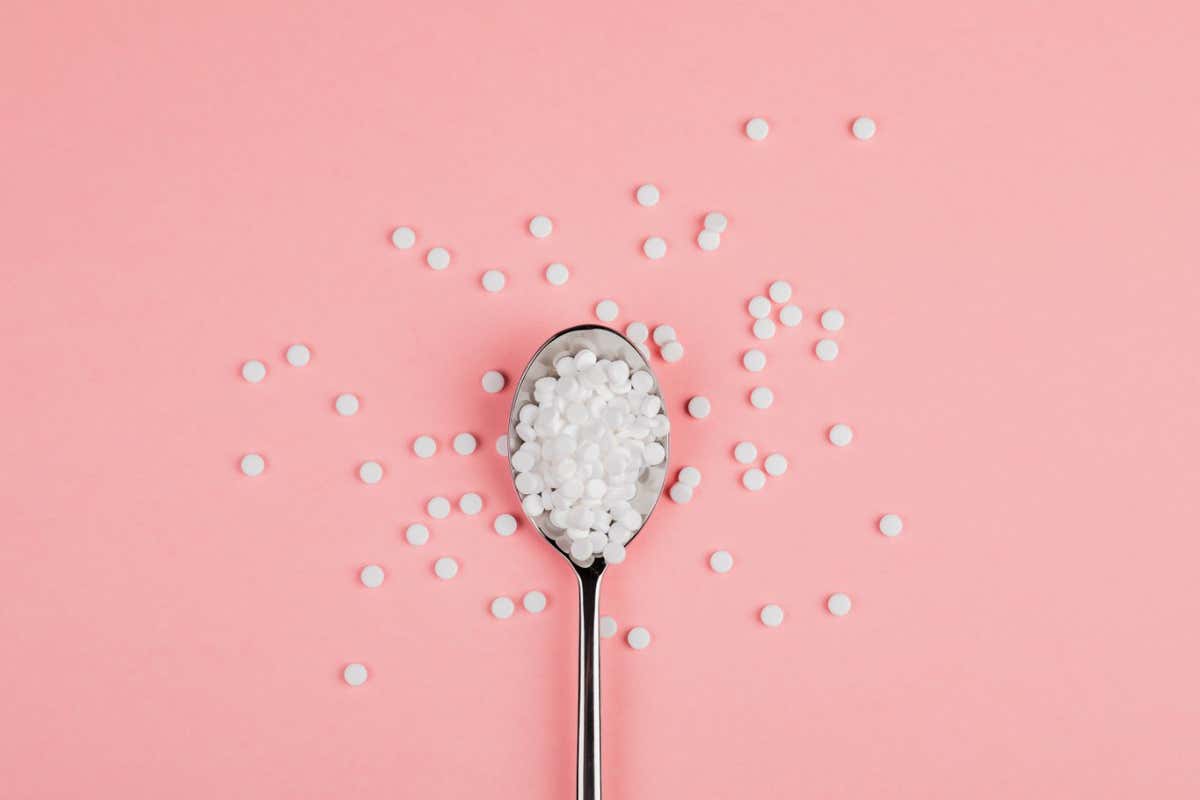 Sugar-replacing tablets with a spoon on a pink background.; Shutterstock ID 1326637646; purchase_order: -; job: -; client: -; other: -